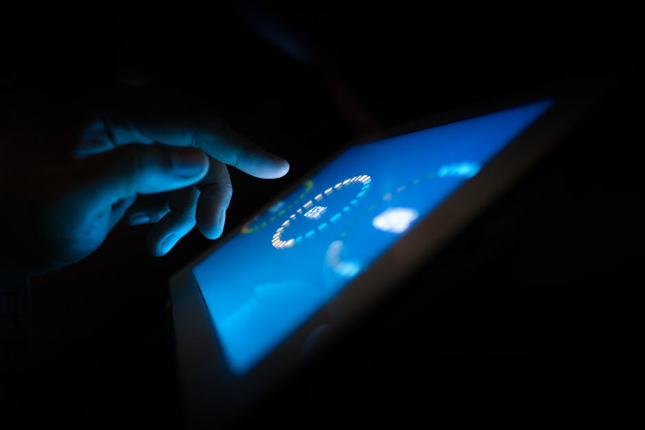 Close-up of a hand interacting with a glowing touchscreen in a dark setting, highlighting technology use.